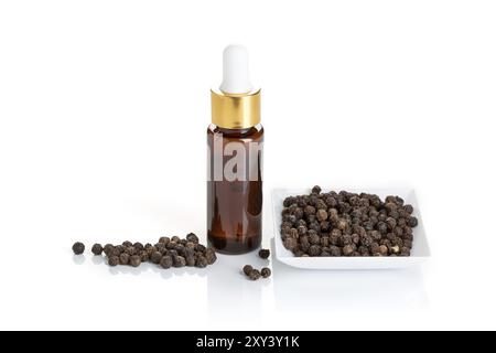 Olio essenziale di pepe nero isolato su fondo bianco. Bottiglia di vetro con olio di pepe nero e contagocce per trattamenti di bellezza, cura della pelle, benessere e purp medicinale Foto Stock