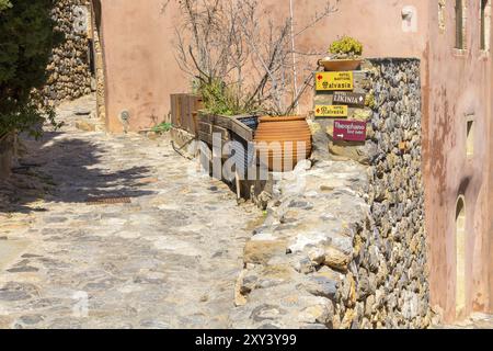 Monemvasia, Grecia, 31 marzo 2019: Vista sulla strada con vecchie case e frecce direzionali dell'hotel nell'antica città, Peloponneso, Europa Foto Stock