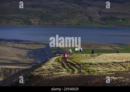 AUSTURLAND, ISLANDA, 20 GIUGNO: Un gruppo di persone fa escursioni lungo il bordo di un canyon vicino alla cascata Hengifoss il 20 giugno 2013 ad Austurland, Islanda, Foto Stock