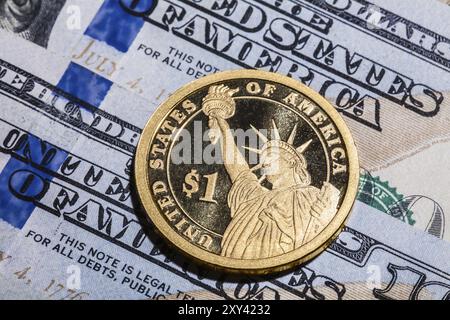 Una moneta da un dollaro, la Statua della libertà, su banconote da cento dollari. Primo piano, colpo macro Foto Stock