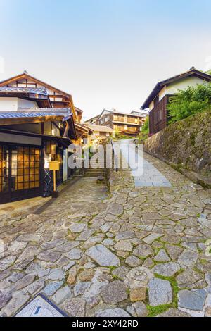 Edifici in legno su un sentiero in pietra inclinata conduce all'ingresso sud della stazione postale di Magome sull'antica sezione Magome-Tsumago del sentiero Nakasendo a Kiso va Foto Stock