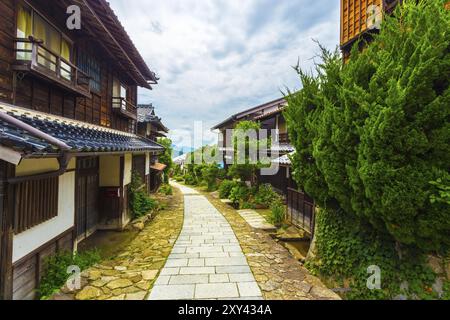 Affacciato su un sentiero in pietra restaurato lungo l'antico sentiero Nakasendo densamente fiancheggiato da tradizionali case in legno sotto nuvole coperte durante il giorno a Magome, Foto Stock