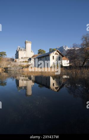 Un castello medievale fiabesco ai piedi delle Alpi francesi che si riflette sul lago di Annecy con le montagne sullo sfondo. Verticale Foto Stock