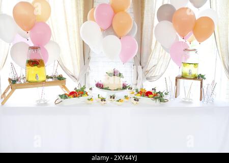 Candy bar con torta e agrumi limonata fatta in casa in una bevanda dispencer. La limonata sullo sfondo di palloncini. Festa di compleanno Foto Stock