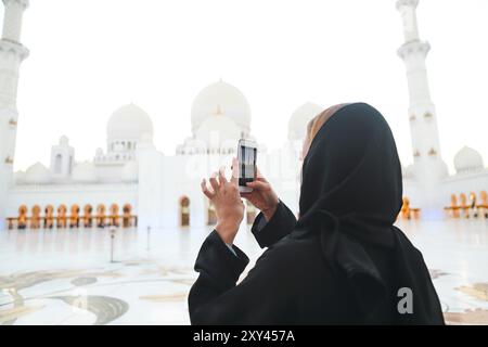 La donna sta immagine di Sheikh Zayed grande moschea dal telefono cellulare Foto Stock