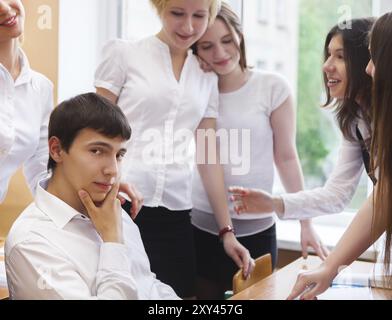 Ritratto di giovane ragazzo in aula con gli amici in background Foto Stock