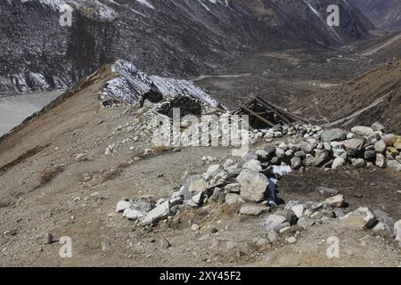 Scena nel Parco Nazionale di Langtang, Nepal. Capanne di pietra senza tetto su un crinale di montagna Foto Stock