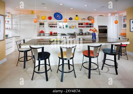 Moderna cucina bianca con accessori e sgabelli colorati Foto Stock