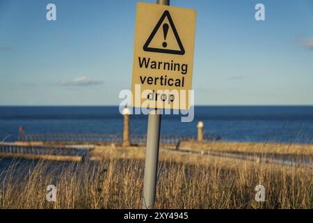 Segno: Avvertenza caduta verticale, visto a Whitby, North Yorkshire, Inghilterra, Regno Unito Foto Stock