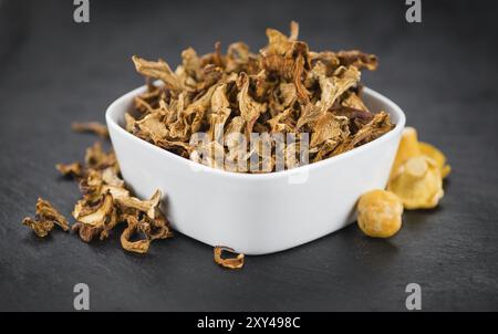 Porzione di Chanterelles essiccate come primo piano dettagliato su una lastra di ardesia, messa a fuoco selettiva Foto Stock