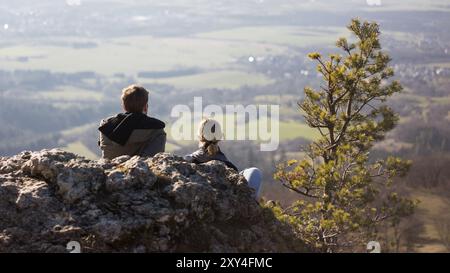 Una coppia si siede su una pietra e guarda giù nella valle Foto Stock