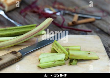 Il rabarbaro fresco viene sbucciato e tagliato per un'ulteriore lavorazione. Il rabarbaro fresco si prepara per la cottura Foto Stock