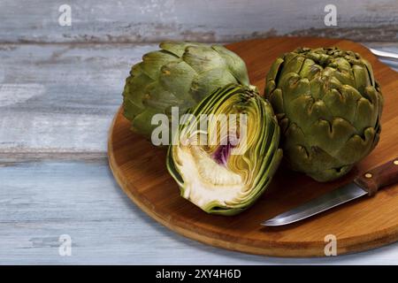 Mature carciofi organico sul tagliere e rustico sfondo di legno Foto Stock