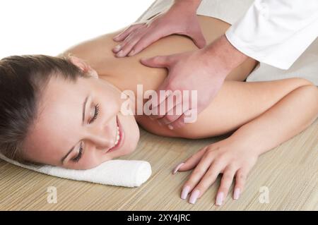 Giovane donna giacente in una spa di ottenere un massaggio, isolato in bianco Foto Stock