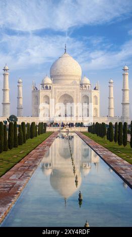 Teleobiettivo distante con vista frontale centrata del Taj Mahal e lunga fontana compressa in primo piano nel giorno del cielo azzurro ad Agra, India. COP. Verticale Foto Stock