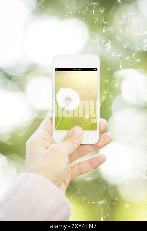 Donna che tiene in mano uno smartphone con fiore su sfondo verde primavera. Concetto di ecologia Foto Stock