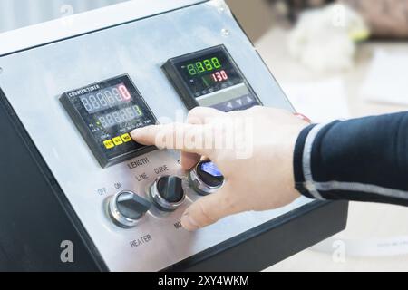 Primo piano dell'operatore, l'operatore preme il pulsante sul pannello di controllo con i dispositivi di controllo nella produzione di mobili. La mano di quell'uomo presse Foto Stock