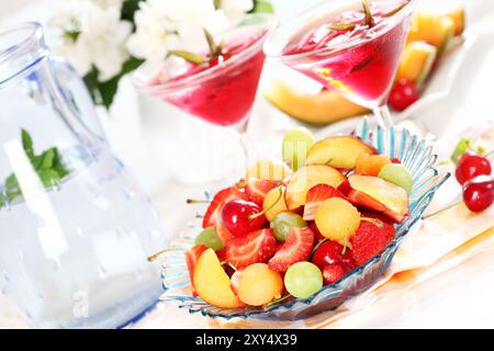 Deliziosa frutta fresca servita in una ciotola con due tè ghiacciati o cocktail Foto Stock