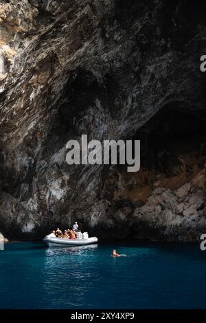 Masua, Italia - 23 agosto 2023: Un gruppo di turisti gode di un tour in barca lungo la costa rocciosa della Sardegna meridionale, vicino a Masua, nuotando nel chiaro tu Foto Stock