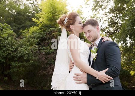 Ritratto ravvicinato di una coppia amorevole di sposi novelli sullo sfondo dei verdi estivi. Il concetto della vita felice dell'Hipster nel matrimonio Foto Stock