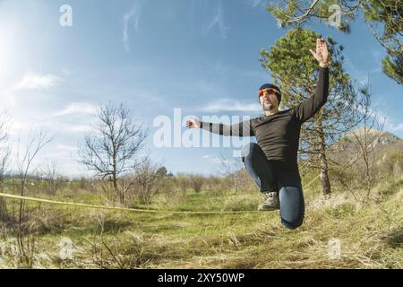 Un uomo all'età di sedersi su una linea lenta, trovare equilibrio e godersi la vita Foto Stock