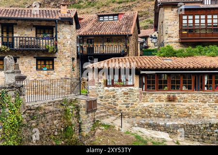 Case rurali di montagna in pietra con verande in legno e tetti di tegole rosse. Bárcena Mayor, Cantabria, Spagna. Foto Stock