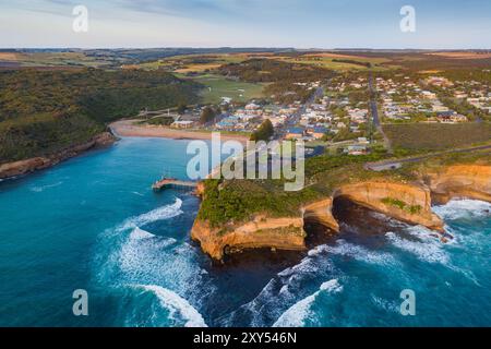 Vista aerea di una città costiera lungo una costa frastagliata con scogliere marine e un piccolo molo a Port Campbell sulla Great Ocean Road a Victoria, Australia. Foto Stock