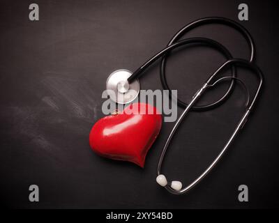 Cuore rosso forma con uno stetoscopio su una lavagna con spazio per il testo Foto Stock