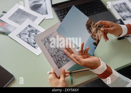 Primo piano di un team creativo che tiene fotografie stampate con paesaggi naturali e collabora allo spazio di copia dei progetti degli editori Foto Stock