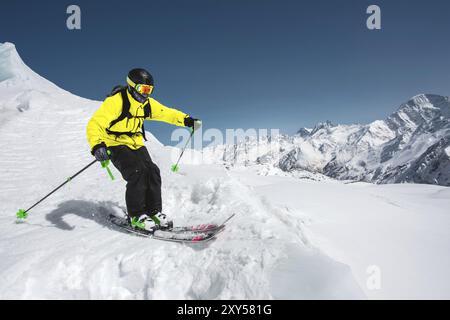 Sciatore professionista alla velocità prima di saltare dal ghiacciaio in inverno contro il cielo blu e le montagne Foto Stock