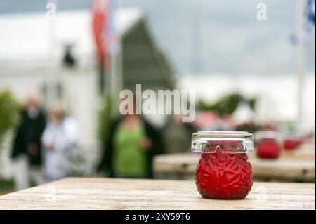 Una candela rossa e un posacenere si trovano su un tavolo nell'area esterna di un pub Foto Stock