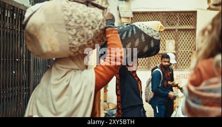 Varanasi, Uttar Pradesh, India. Le donne indiane portano le cose sulle loro teste e guardano la fotocamera. Smile Women che va in strada Foto Stock