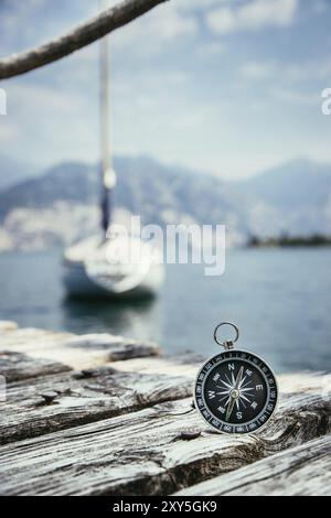 Compass giacente sul dock in legno pier in primo piano, barche a vela in sfondo sfocato Foto Stock