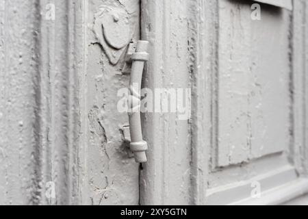 Chiusura di buchi con tende e maniglia sul grigio molte volte dipinta porta vintage in legno a doppia canna incrinata del secolo scorso con una pos Foto Stock