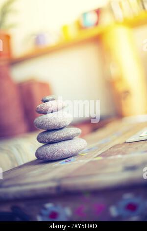 Feng Shui: Cairn di pietra in primo piano, salotto sfocato sullo sfondo. Equilibrio e relax Foto Stock