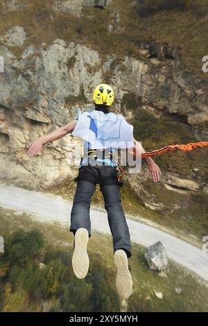 Un uomo in un casco salta ropeup con una bandiera vuota in montagna. Sport estremi. Tempo libero. Vista dall'alto Foto Stock