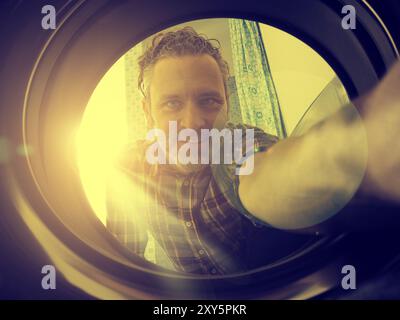 Uomo felice il caricamento della macchina di lavaggio, con sole splendente nel retro, golden piatto stile di colore Foto Stock