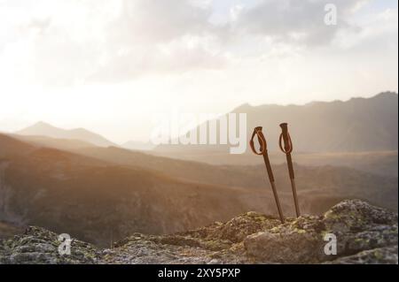 Bastoni professionali per arrampicarsi su una montagna vicino a una pietra su un sentiero di alta montagna contro un cielo blu e nuvole bianche al tramonto. Il concetto di attivo Foto Stock