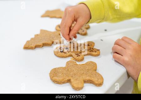 Le mani dei bambini decorano biscotti fatti in casa con gocce di cioccolato Foto Stock