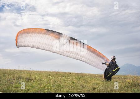 Il parapendio apre il suo paracadute prima di decollare dalla montagna nel Caucaso settentrionale. Riempimento dell'ala paracadute con aria prima del decollo Foto Stock