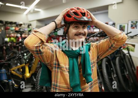 Ritratto di un uomo sorridente ciclista che indossa il casco di sicurezza al negozio di articoli sportivi Foto Stock
