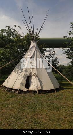 Tepee bianca in tela in piedi nella foresta in una giornata di sole Foto Stock