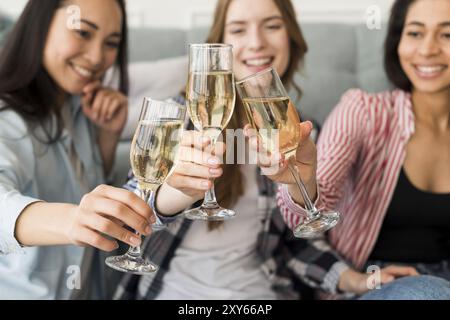 Sorridenti ragazze sedute che tengono gli occhiali che lo aggraffano insieme Foto Stock