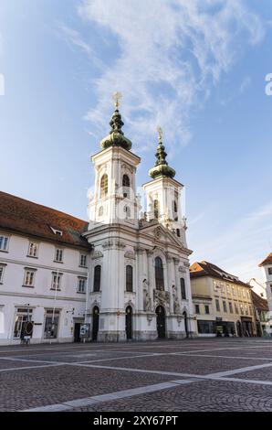 Austria, 20.01.2019: Veduta alla Chiesa Mariahilf due torri e piazza nel centro della città vicino al fiume Mur, sole invernale destinazione di viaggio, Europa Foto Stock