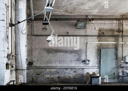 Lampada in una postazione di lavoro in un'officina abbandonata e in disuso Foto Stock