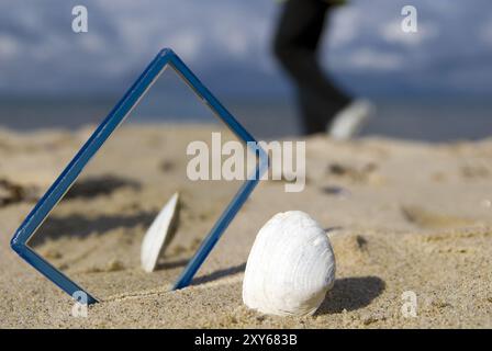 Conchiglia e specchio sulla spiaggia Foto Stock