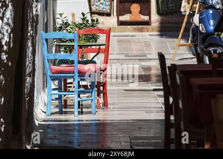 Nafplio, Grecia città vecchia vista con il rosso e il blu colorato tavolo e sedie in piccoli street cafe in Nafplion, PELOPONNESO Foto Stock