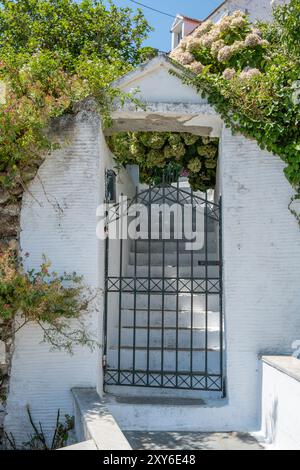 Grecia. Cancello metallico chiuso, scale in pietra imbiancate di bianco ingresso tradizionale in un'isola greca, soleggiata giornata estiva. Foto Stock