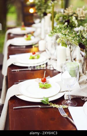 La decorazione della tavola di nozze con vasi di cristallo, fiori e antipasti in stile botanico nel giardino Foto Stock