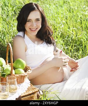 Ritratto di bella donna incinta in bianco nel Parco di primavera Foto Stock